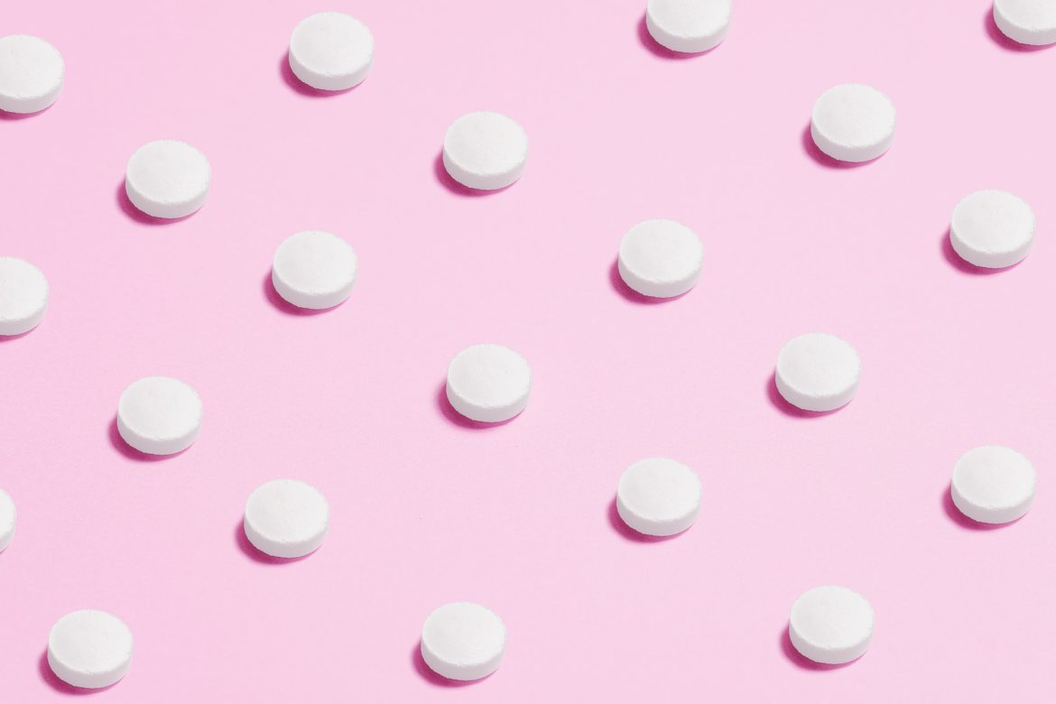 Einzelne Pillen im Polkadotmuster vor rosafarbenem Grund